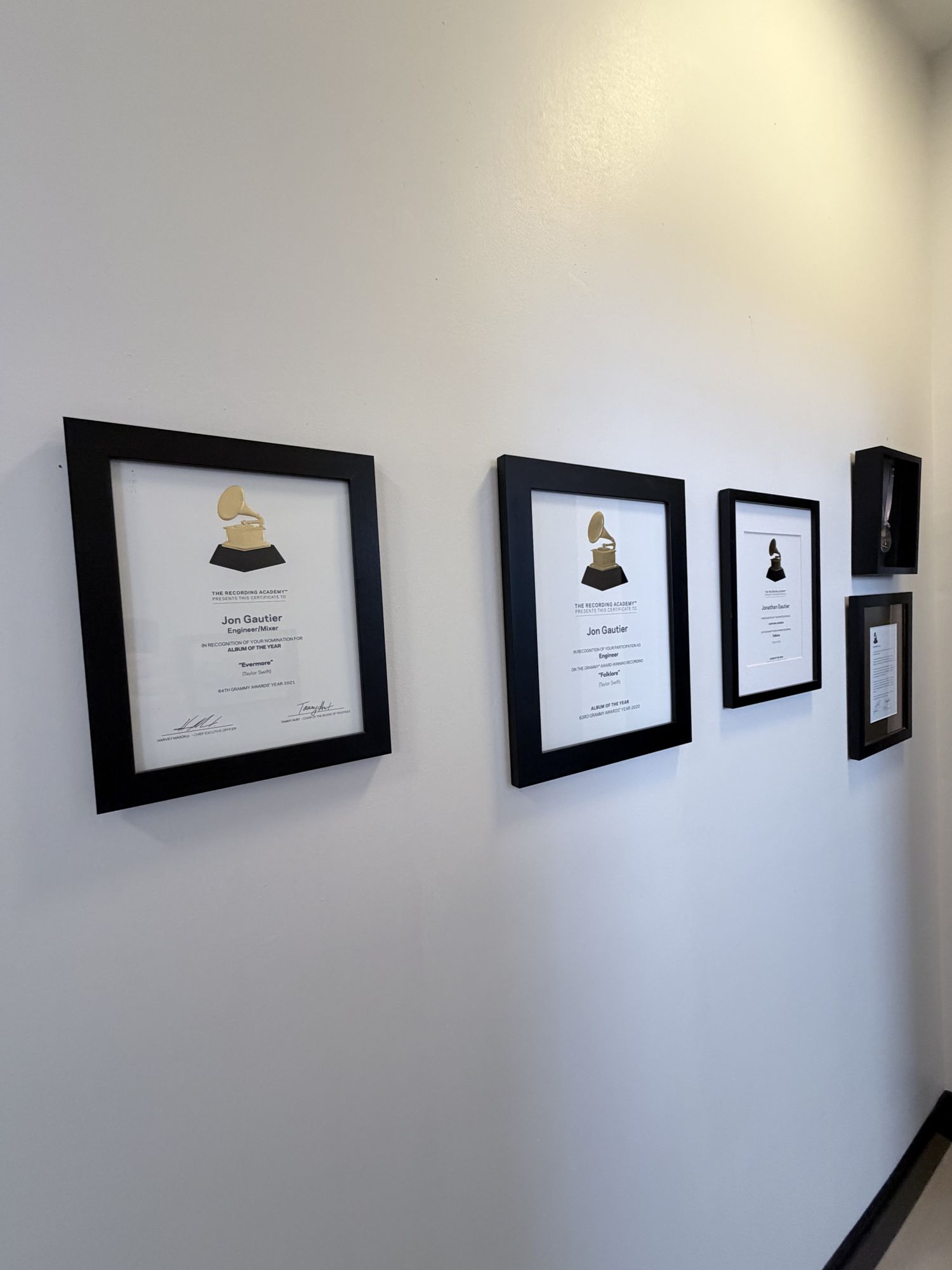 Framed Grammy certificates on the wall at Sound House Studios — Jon Gautier's Folklore engineering credit and Evermore Album-of-the-Year nomination